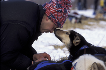 Dog and musher touching noses in winter